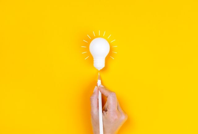 ペンで電球を指す女性の手